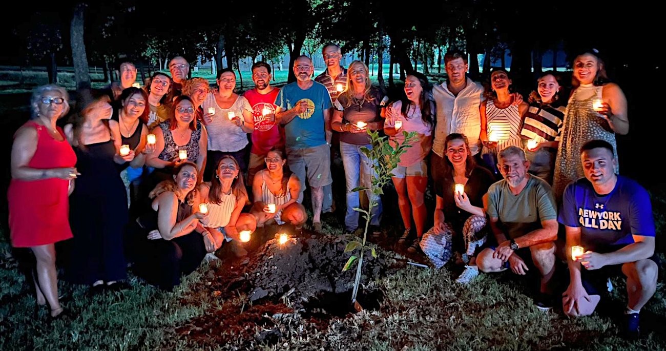 Toma exterior nocturna en el Parque Taborin. Algo más 
					de 20 integrantes de los Equipos de Pastoral del colegio posan, cada uno con una vela encendida
					en la mano, alrededor de un árbol recién plantado.